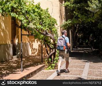 Senior adult photographer strolls through the Huerto de Calixto y Melibea gardens near the cathedrals in Salamanca Spain. Photographer walks through the gardens in Salamanca Spain