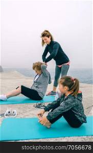 Senior and young woman exercising with little girl sitting. Women exercising with little girl sitting