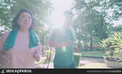 Senior asian couple running together inside the park on hot sunny morning, family get together, healthy activities, human aging process, retirement lifestyle, elderly social community gathering