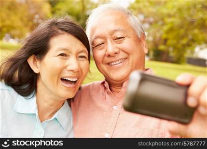 Senior Asian Couple Taking Selfie In Park Together
