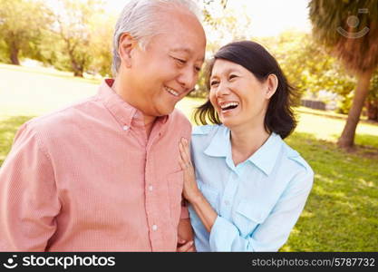 Senior Asian Couple Walking Through Park Together