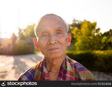Senior Asian man with a loincloth covering his shoulders, standing over the bright sky background.