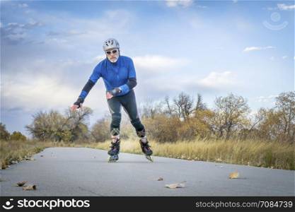 Senior athletic male inline skating on the Poudre RIver Trail in Colorado, late fall scenery