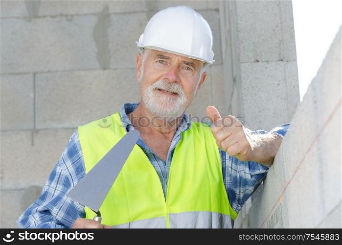 senior builder using a hammer to remove walls plaster