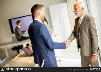 Senior business man handshaking with his young colleague in the office
