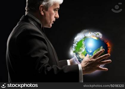 Senior business man holding planet in his arms and controlling it