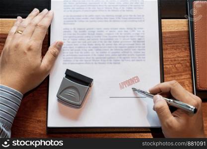 senior business man male hand putting or signing signature in the certificate contract after approve stamp on loan document agreement lawyer hand concept