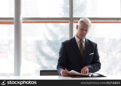 senior business man reading magazine at modern bright office