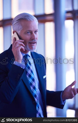 senior business man talk on mobile phone at modern bright office interior