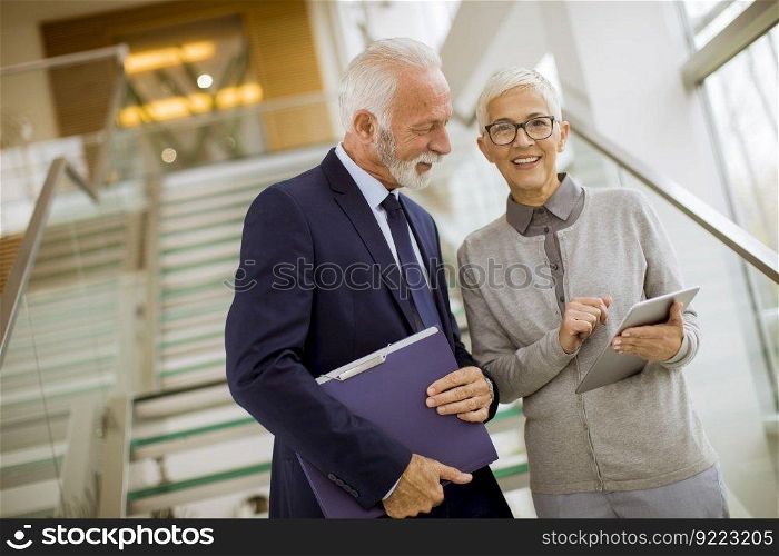 Senior business people standing in office with tablet and paper documents