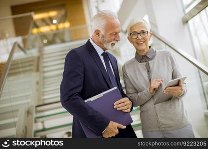 Senior business people standing in office with tablet and paper documents