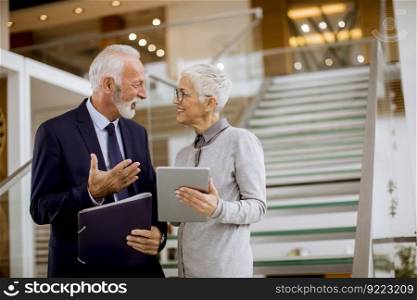 Senior business people standing in office with tablet and paper documents