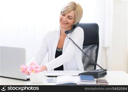 Senior business woman speaking phone and working on laptop