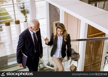 Senior businessman and businesswoman walking and taking stairs in an office building