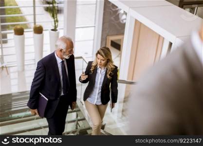 Senior businessman and businesswoman walking and taking stairs in an office building