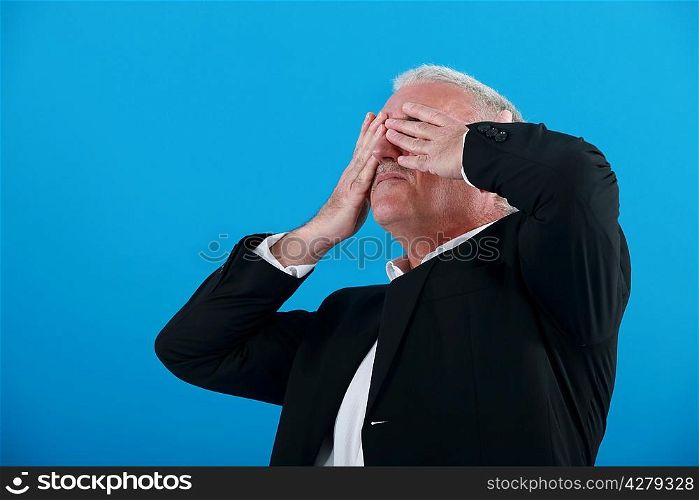 senior businessman covering his eyes with his hands