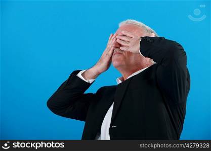 senior businessman covering his eyes with his hands