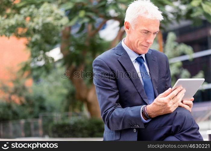 Senior businessman holding touchpad . Senior businessman holding touchpad outdoors