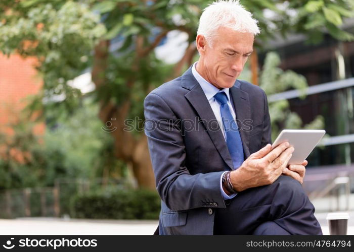 Senior businessman holding touchpad . Senior businessman holding touchpad outdoors