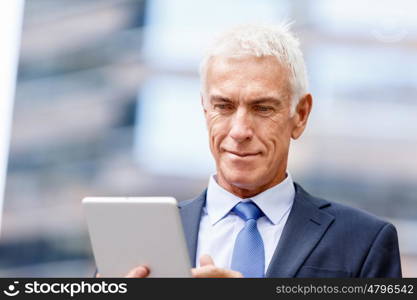 Senior businessman holding touchpad . Senior businessman holding touchpad outdoors