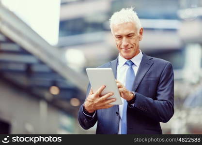 Senior businessman holding touchpad . Senior businessman holding touchpad outdoors