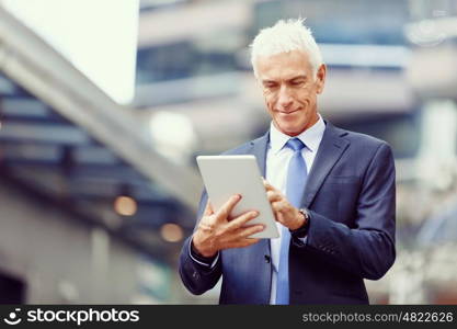 Senior businessman holding touchpad . Senior businessman holding touchpad outdoors