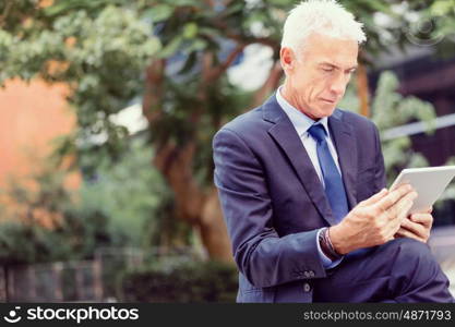 Senior businessman holding touchpad . Senior businessman holding touchpad outdoors