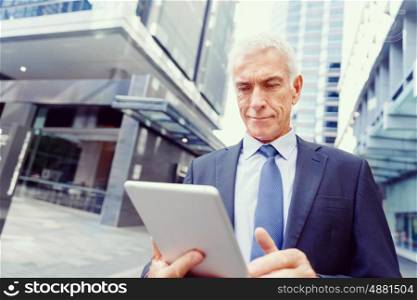 Senior businessman holding touchpad . Senior businessman holding touchpad outdoors