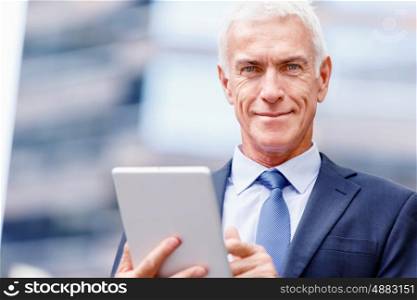 Senior businessman holding touchpad . Senior businessman holding touchpad outdoors