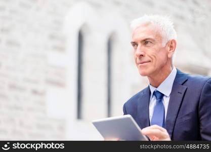 Senior businessman holding touchpad . Senior businessman holding touchpad outdoors