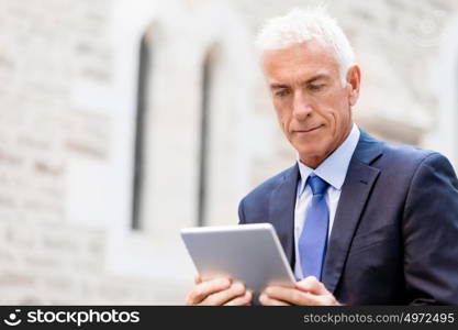 Senior businessman holding touchpad . Senior businessman holding touchpad outdoors