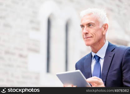 Senior businessman holding touchpad . Senior businessman holding touchpad outdoors