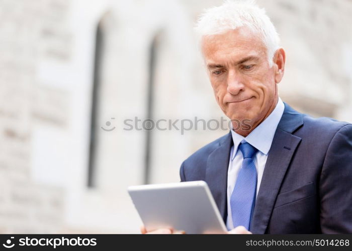 Senior businessman holding touchpad . Senior businessman holding touchpad outdoors