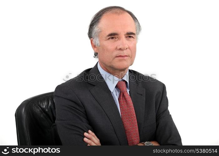Senior businessman sat with his arms crossed
