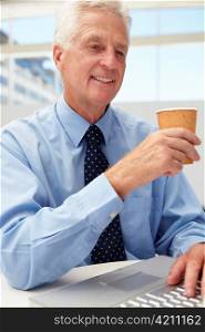 Senior businessman with laptop and coffee