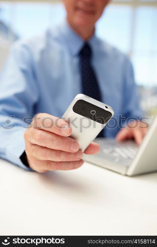 Senior businessman with laptop and phone