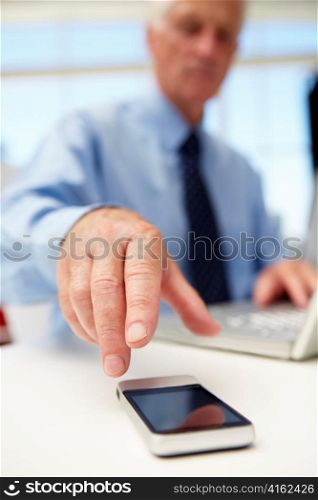 Senior businessman with laptop and phone