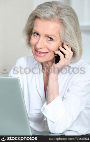 Senior businesswoman in the office talking on the phone