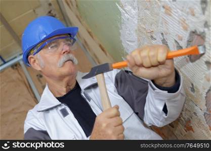 senior carpenter working with a hammer and chisel