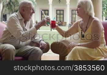 Senior caucasian couple sitting in bar at hotel with cocktails and talking