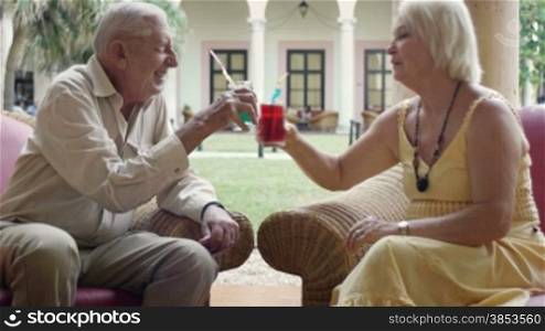 Senior caucasian couple sitting in bar at hotel with cocktails and talking