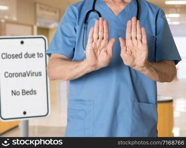 Senior caucasian doctor in scrubs in hospital stopping entry because no beds available because of coronavirus or flu. Senior doctor in scrubs refusing entry to hospital because of Corona Virus