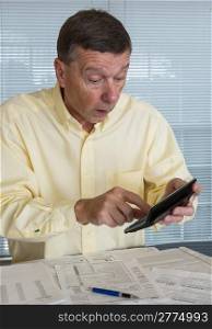 Senior caucasian man preparing tax form 1040 for tax year 2012 showing shock at amount of tax owed
