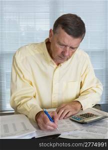 Senior caucasian man preparing tax form 1040 for tax year 2012 with receipts and calculator