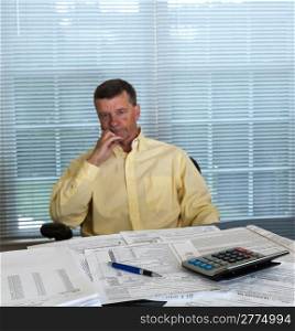 Senior caucasian man weary from preparing tax form 1040 for tax year 2012 with calculator