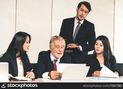 Senior caucasian manager working in office with assistance of young Asian business people and translator in the meeting. Corporate international business and secretary language translation concept.