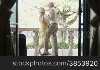 Senior caucasian wife and husband on vacation, dancing on terrace in hotel
