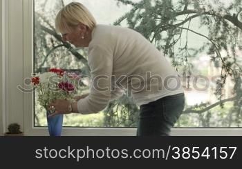Senior caucasian woman with bunch of flowers in living room at home. Dolly shot