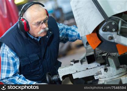 senior caucasian worker wearing earphones is in the ironworks