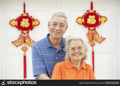 Senior Chinese Couple Outside Home Decorated With Welcoming Feng Shui Banners
